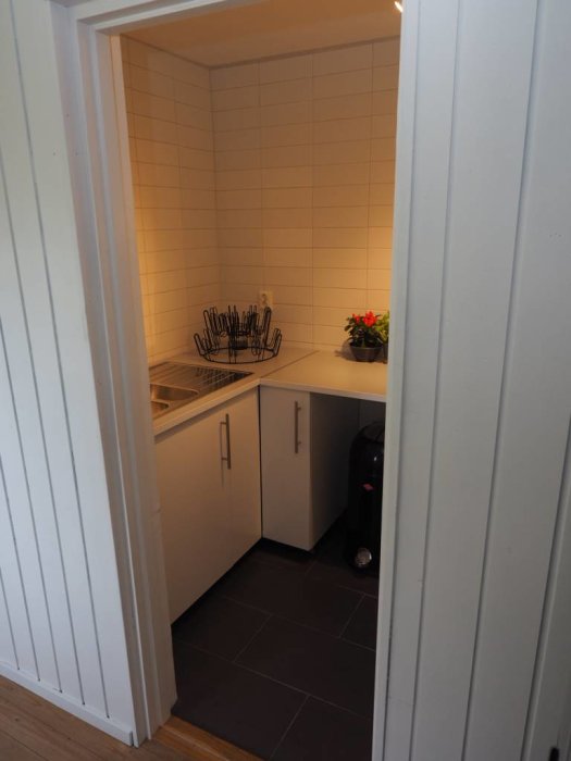 Renoverat köksutrymme med vit kakelvägg, skåp och nyinstallerat uttag för spis.
