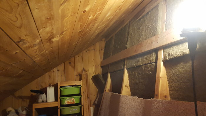 Innertak i trä med synliga stödben och spikade reglar mot isolering, redo att renoveras.