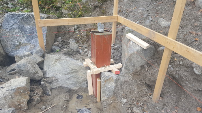 Nyguuten betongplint med träform, omgiven av sten och stöttor i byggarbetsmiljö.