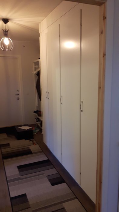 Nymonterade vita garderobsdörrar med handtag, vid en trärammad öppning, inomhusmiljö.