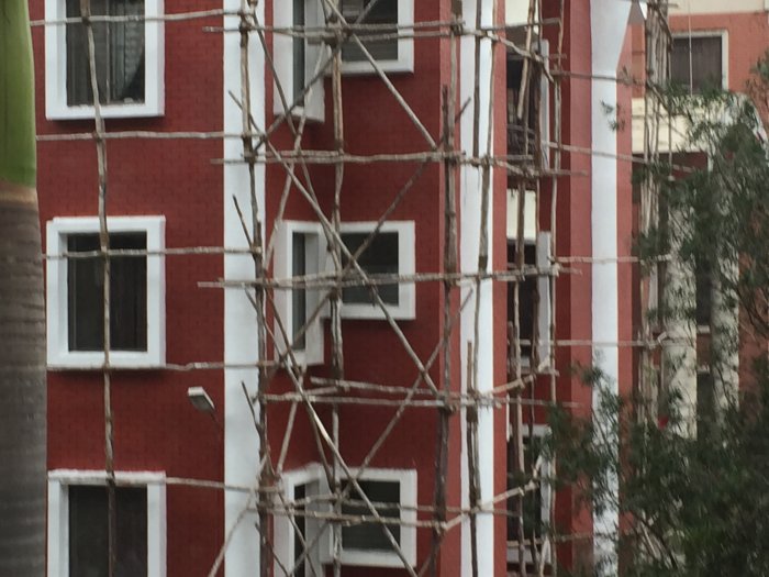 Bamboo scaffolding on a red and white building under construction in India.