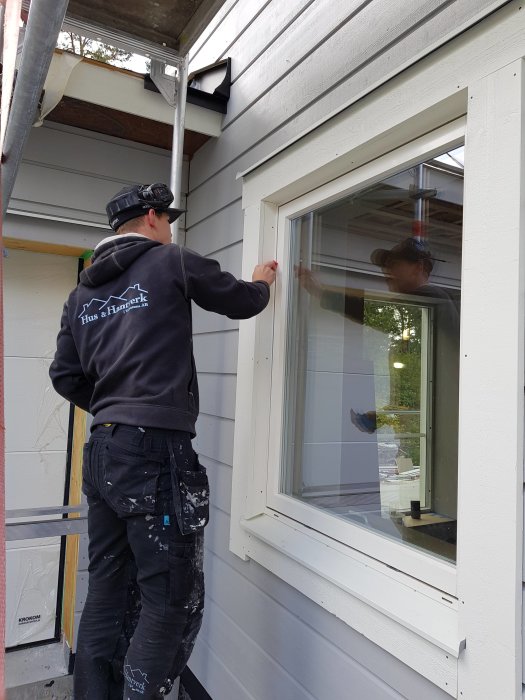 Snickare arbetar med att installera fönstersmygar och foder på husfasad.