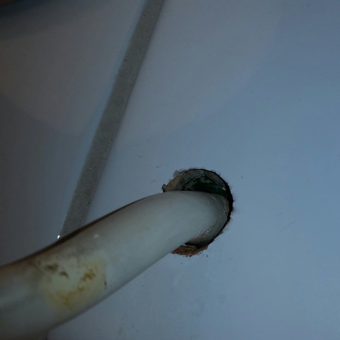 Elektrisk kabel som kommer ut genom ett hål i en vit badrumsvägg, behov av tätningsåtgärd.