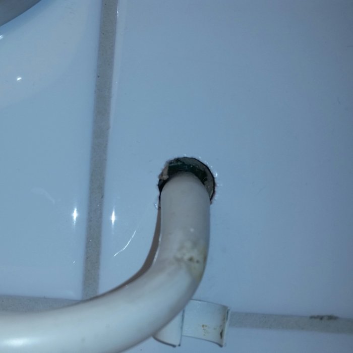 Elkabel kommer ut genom ett hål i kaklad badrumsvägg, behov av tätning synlig.