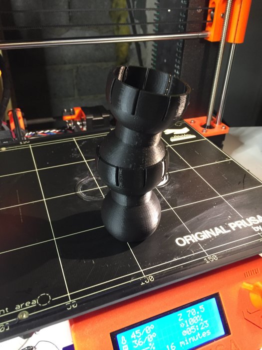 3D-utskrift av ett svart objekt med skålliknande form på en Prusa-printers byggyta.