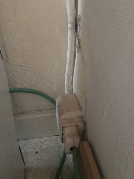 Eluttag med utanpåliggande eldragning och synlig kabel genom en vägg.