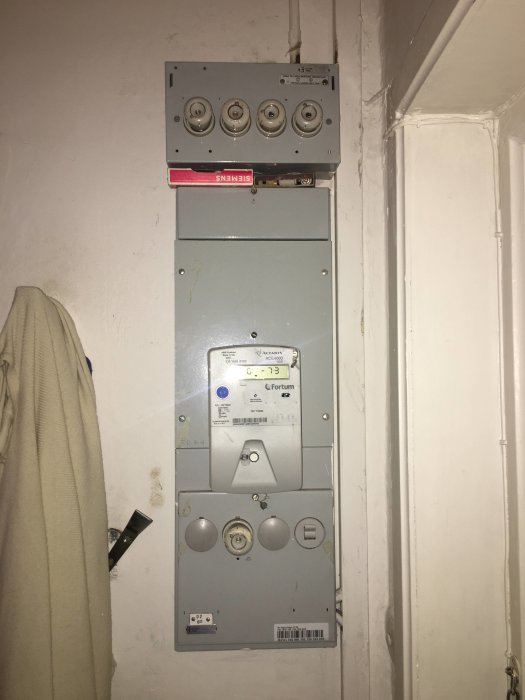 En elcentral med säkringar, mätare och uttag på en vägg som ska renoveras.