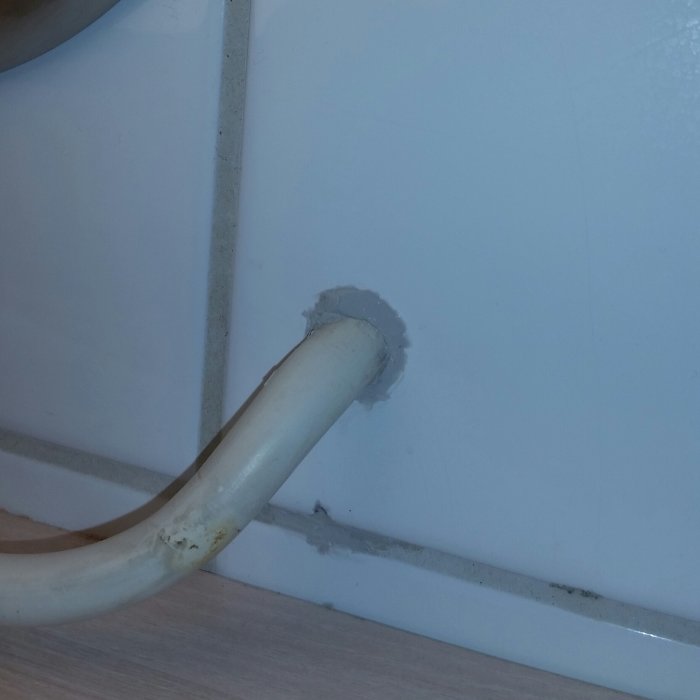 En rörinstallation gående genom en vit vägg med tätning kring röret.