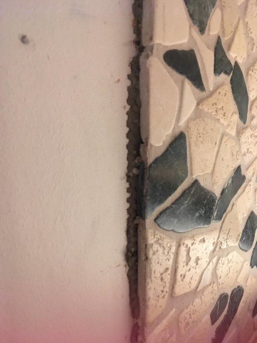 Stenplattor fastsatta på köksvägg med synligt fix och liten glipa vid väggen.
