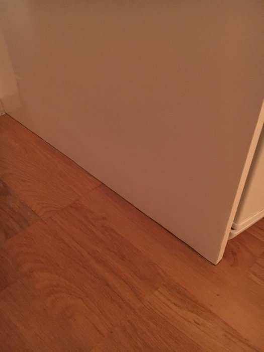 Gammal parkettgolv med list vid skåpets täcksida i ett hörn av rummet.