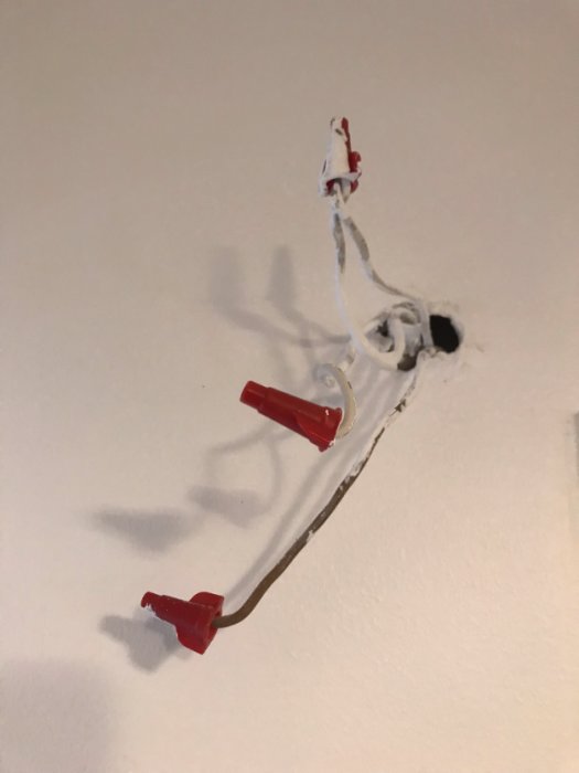 Vägg med fyra oskyddade elledningar varav två är hopslingrade, utan monterad dörrklocka.