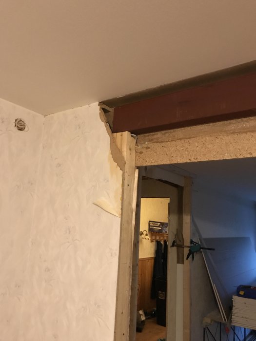 Delvis nedmonterad vägg med synlig stödbalk i en bostad under renovering.