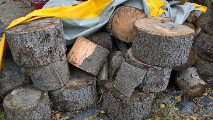 Trave av avkapat ved och bjälkar i olika storlekar, staplade utomhus.