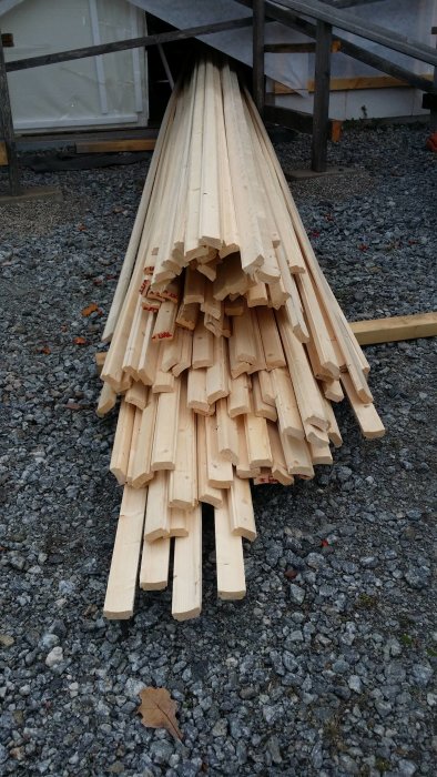 En hög med nykapade lockläkter på grusunderlag redo för målning och montering.