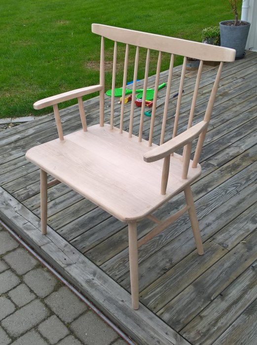 Obehandlad pinnstol i bokträ på en träterrass, redo för ytbehandling.