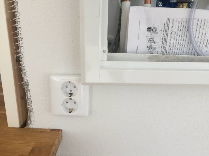 Eluttag placerat för nära ett infällt skåp i en murad vägg, vilket hindrar montering av ramen.