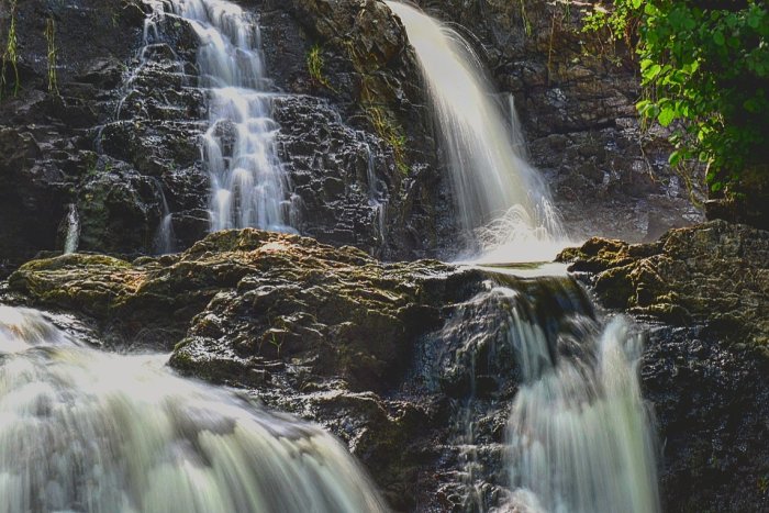 Bild på en liten vacker vattenfall i skogen, tagen utan stativ med lång exponering.