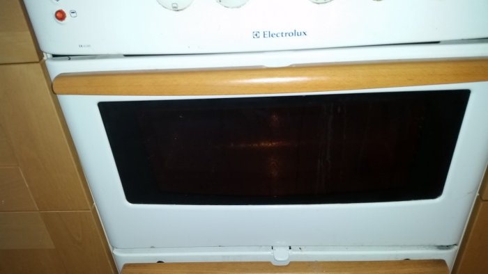 Vit Electrolux-spis med ugnslucka och kontrollpanel, en lampa på fronten sitter löst.