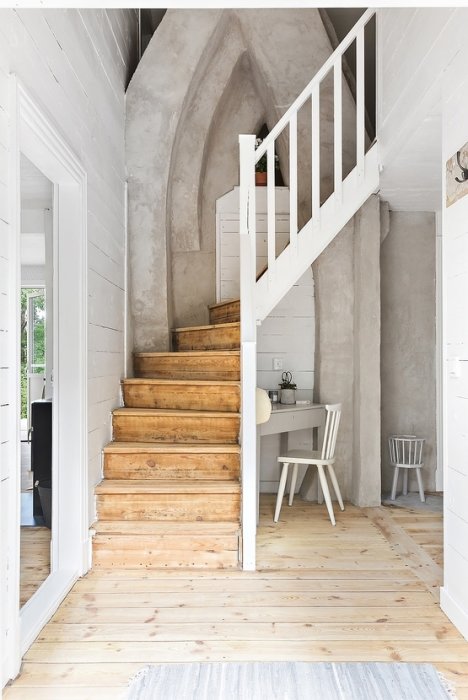 Imponerande murstock i ett hem med trätrapp, vitmålade väggar och rustik känsla.