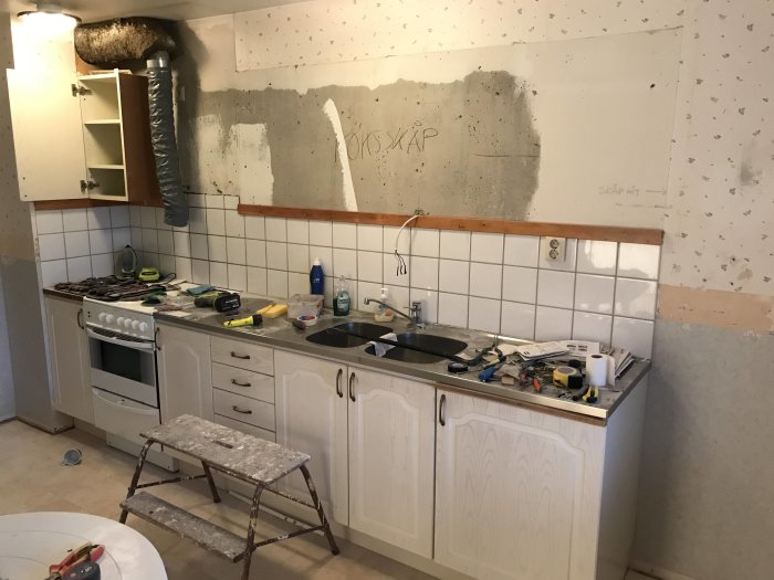 Nedmonterat kök med verktyg på bänkar och avlägsnat kakel, redo för renovering.