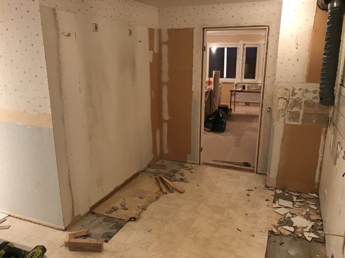 Rivet kök med borttagna skåp, synliga ledningar och kakelspill på golvet, redo för renovering.