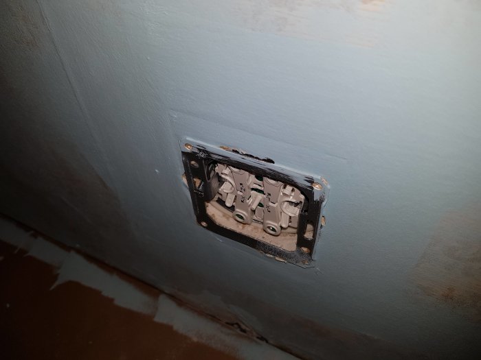 Elektrisk vägguttag utan täckplatta som visar interna komponenter och ledningar.