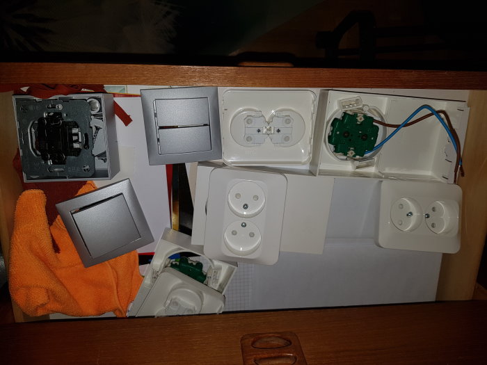 Olika elinstallationskomponenter som strömbrytare och uttag utspridda på ett bord.