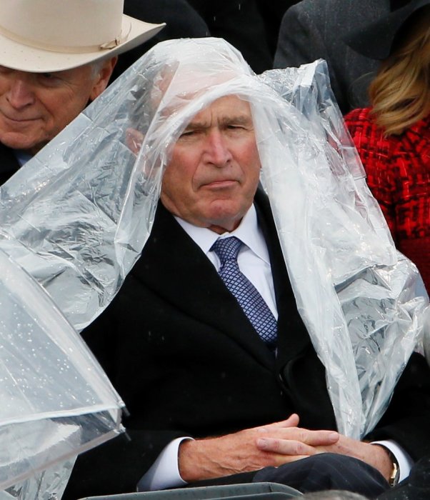 Man i kostym skyddar sig mot regn med en genomskinlig plastponcho.