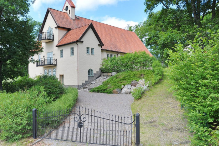 Omvandlad kyrka till bostad i Strängnäs, vita väggar och tegeltak, med balkong och grind.