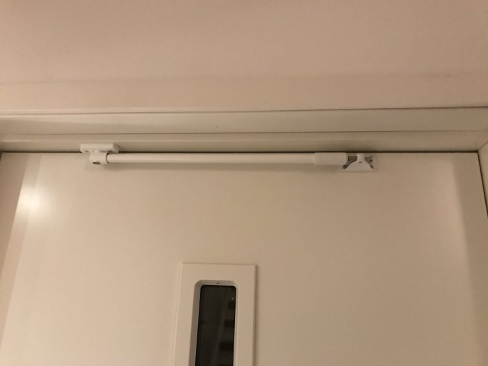 Elektrisk ledning dold ovanför dörr i kabelskydd mot ljus vägg och tak.