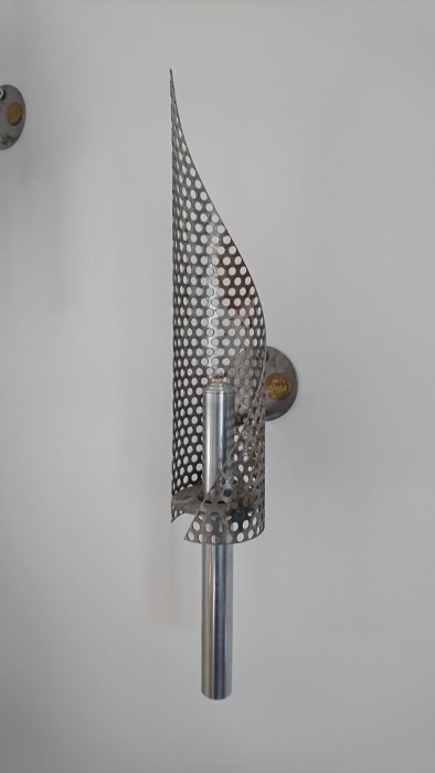 Väggmonterad 90-tals oljelampa i metall med spiralformad skärm och cylindrisk behållare.