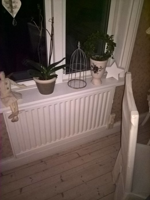 Värmeelement i rum med dekorativa föremål på fönsterbrädan, inga oljeelement synliga.