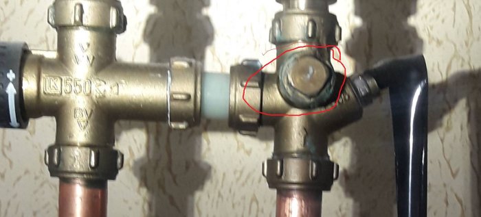 VVS-installation med mässingsfördelare och en säkerhetsventil inringad med rött, föreslagen för byte.