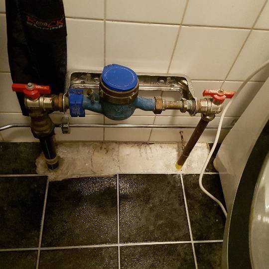 Vattenmätare och ledningar i en tvättstuga, visar hur vattnet kommer in från krypgrunden.