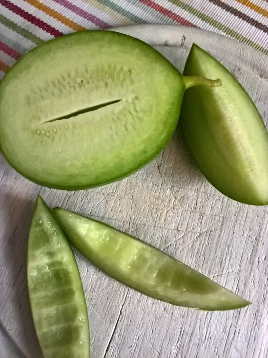 Halverad och klyftad grön melon på ett randigt tyg.