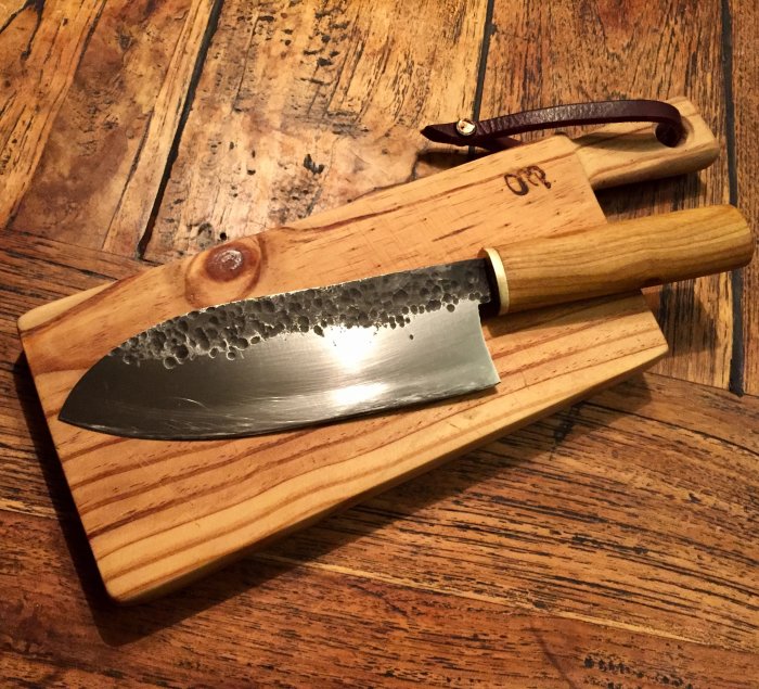 Hantverksmässigt kniv och skärbräda i trä på ett bord, framstår tunga och välbalanserade.
