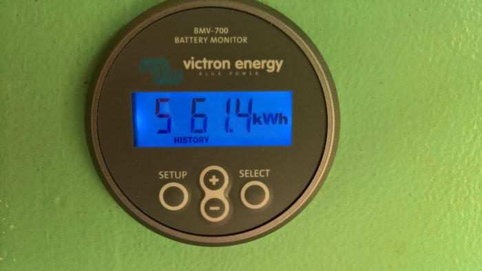 Victron Energy batterimonitor som visar 5614 kWh förbrukad energi på en grön vägg.