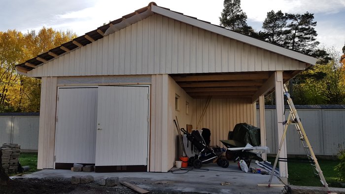 Nyinstallerade vindskivor och vindskiveplåtar på ett nästan färdigt garagebygge, med en minskande jordhög i förgrunden.