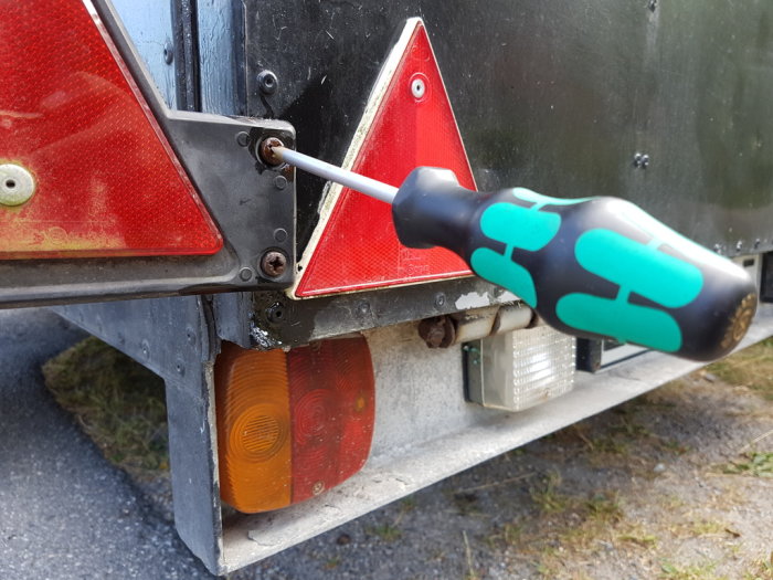 Skrutmejsel med lasertip som avlägsnar fastrostad skruv från ett släpvagnslyse.