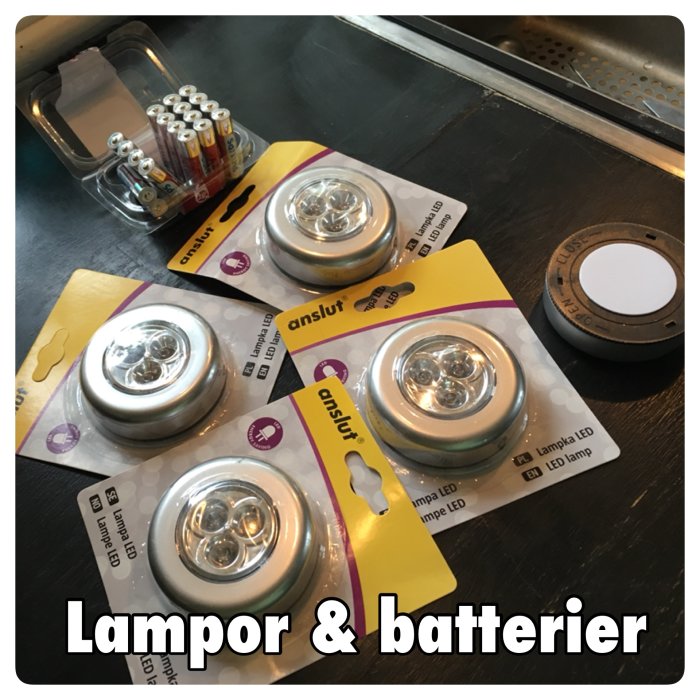 Batteridrivna LED-lampor i förpackningar och ett set batterier på ett mörkt bord.