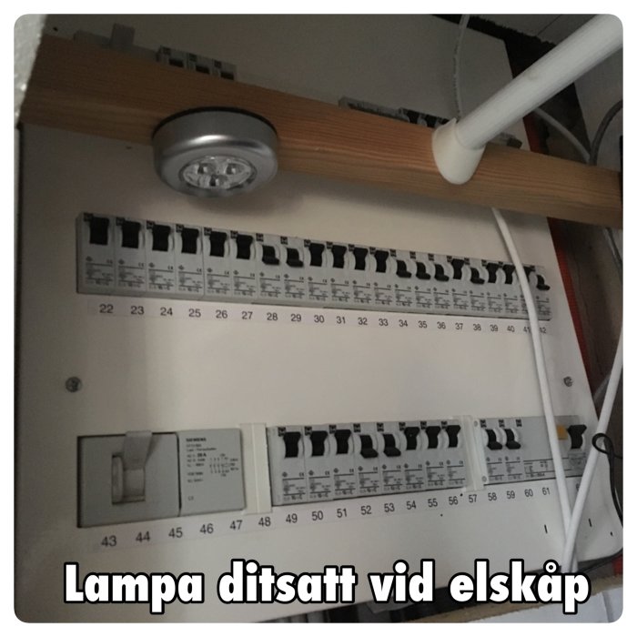 Batteridriven ledlampa monterad ovanför säkringarna i ett elskåp.