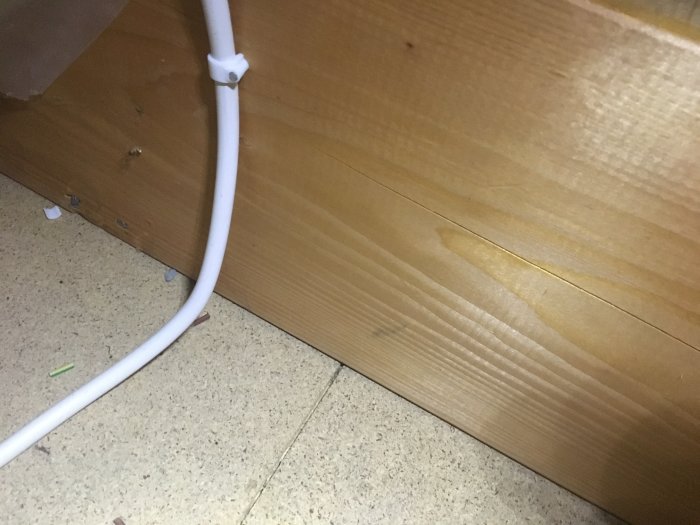 Elledning fäst längs med en träsockel på ett mönstrat golv.