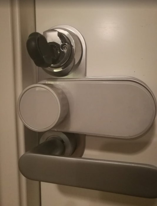 Ett dörrhandtag med låscylinder och nyckel i en dörr, troligen en modifiering med Biltemas cylinder.