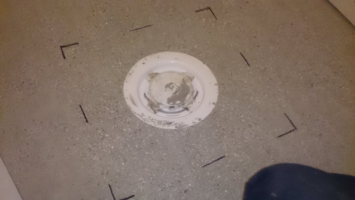 En betongbrunn i golv före tätskikt med måttemarkeringar.