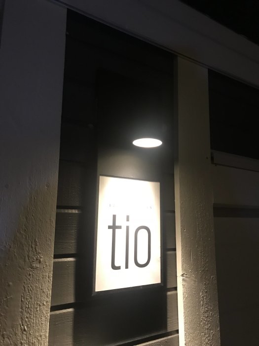 Nyinstallerad lampa tänd ovanför fönster med texten "tio" på kvällstid.