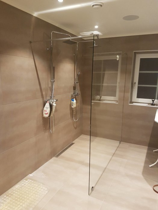 Nyligen installerad duschvägg i ett badrum med kakel och duschinstallationer.