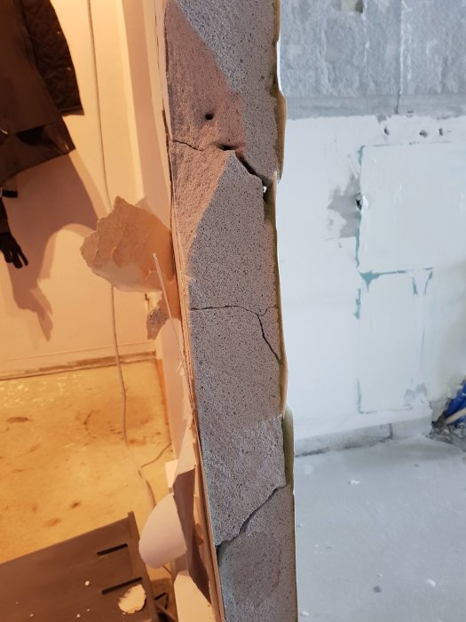 Sprucken lättbetongvägg med lösa bitar, synlig skada under köksrenovering.