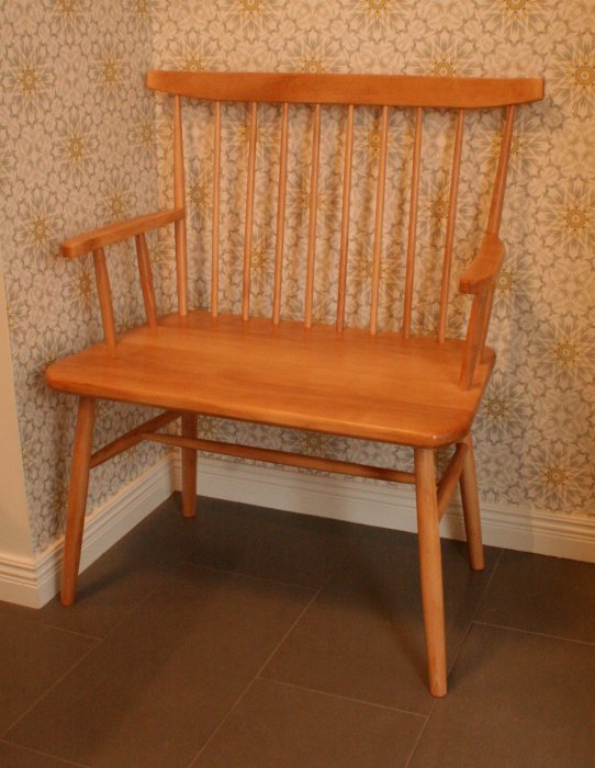 Träbänk behandlad med Danish oil mot en tapetserad vägg, ger en varm honungsfärgad finish.