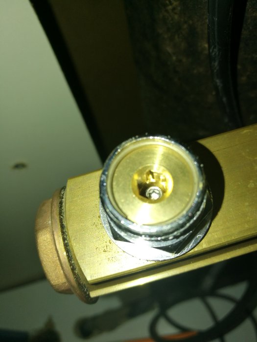 Närbild av en ventiltopp med torx skruv för justering av flödet i en golvvärmesystem.