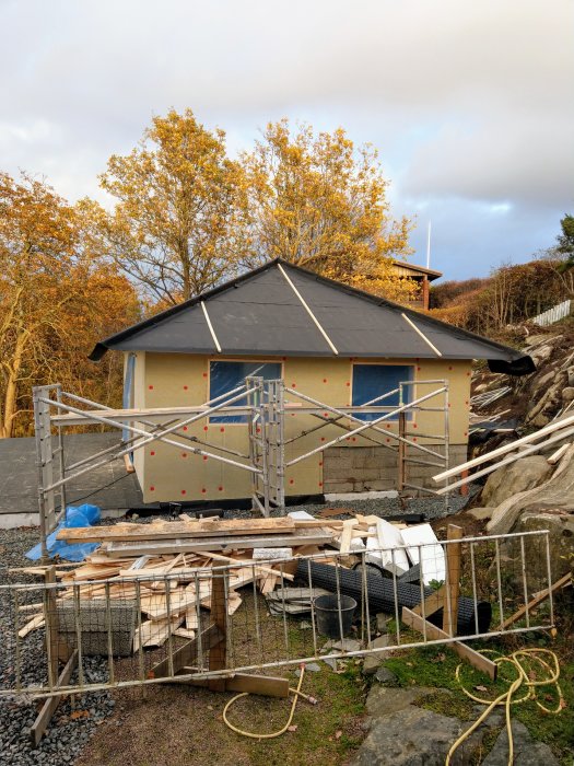 Ett hus under renovering med byggnadsställningar och byggmaterial runtom.